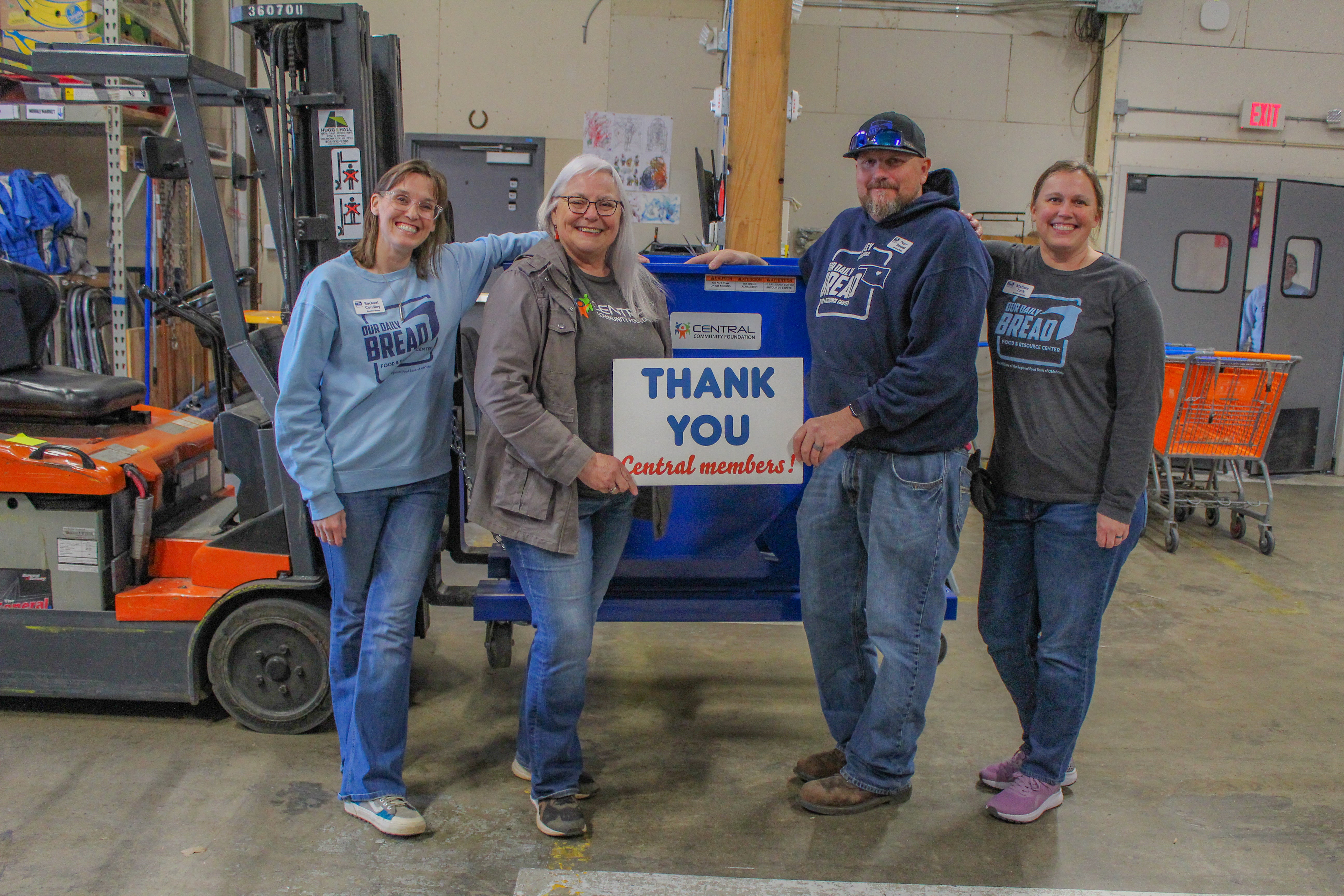Our Daily Bread Director Rachael Condley, Central Community Foundation board member Donna Dollins, Our Daily Bread Warehouse Manager Trevor Steward, and Assistant Director Melissa Tuck stand in front of the Steel Dumping Hopper, which was purchased with funds from a Central Community Foundation grant.